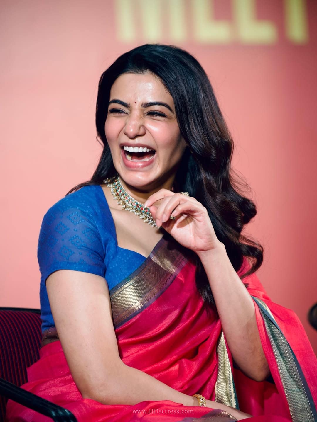 Samantha Ruth Prabhu smiling gracefully and showcasing her baby bump in an elegant red designer saree.