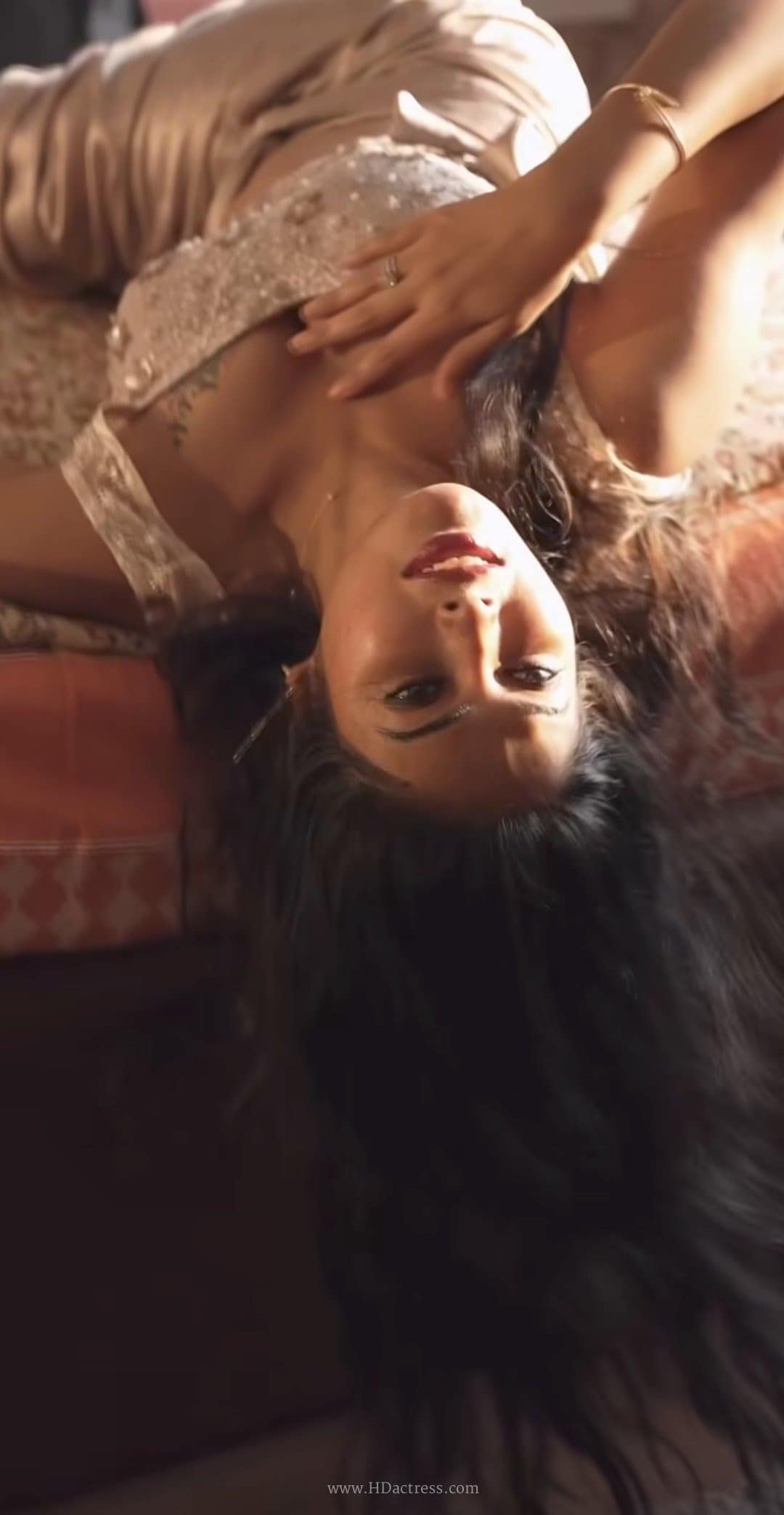 Divi Vadthya posing playfully on a bed in a sultry, glamorous outfit.