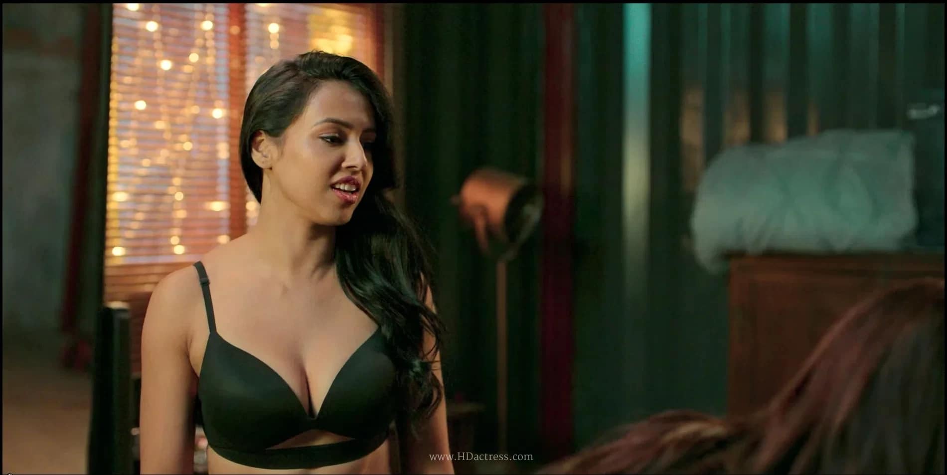 Aditi Shetty posing confidently to showcase her toned physique in a black push-up bra with intricate strappy cut-out details under the bust.