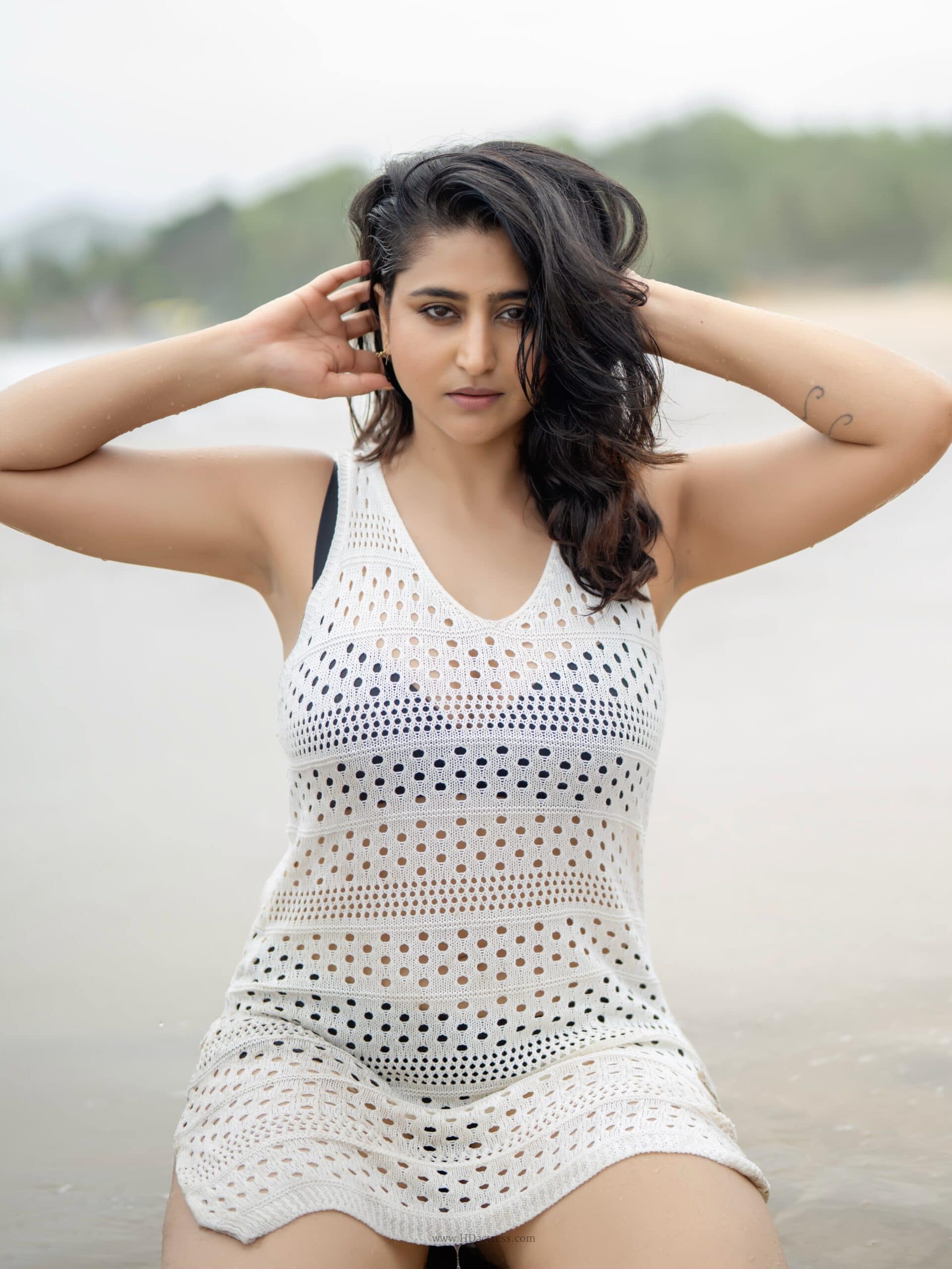 Varshini Sounderajan posing confidently in a sheer, sleeveless V-neck mesh cover-up dress highlighting a bold celebrity fashion statement.